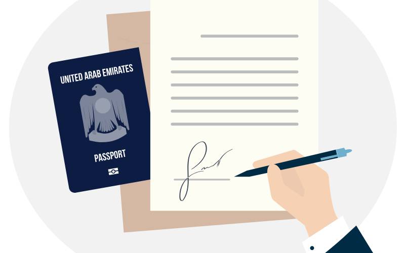 A person signing an application form with passport aside it.