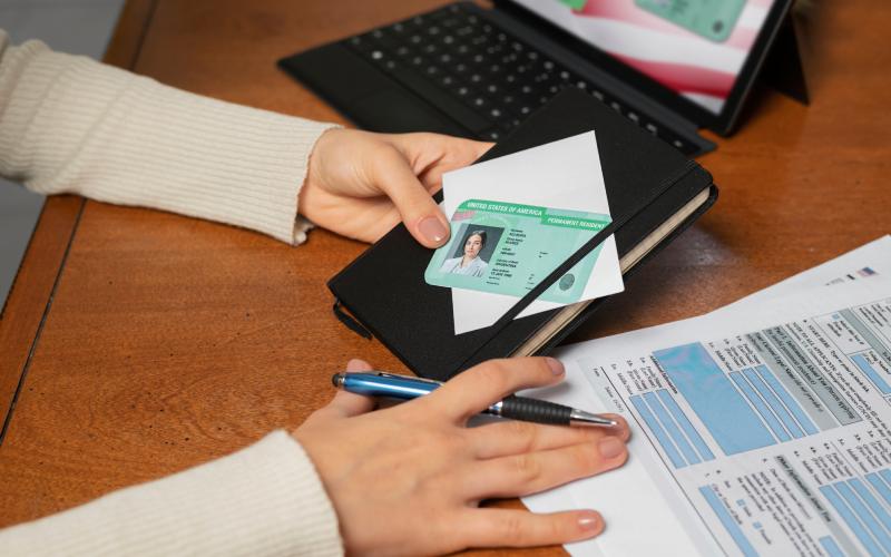 Woman holding a green card & pen for visa application